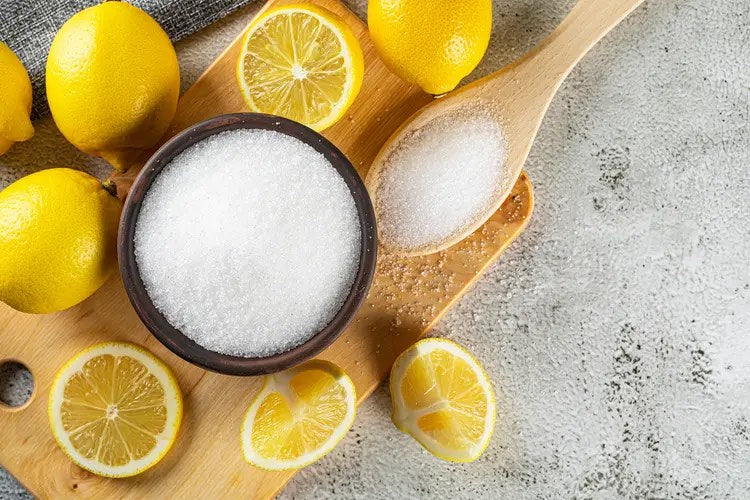 Lemons beside a bowl of citric acid