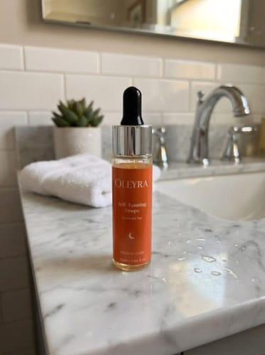 Customer photo of an Oleyra tanning drops bottle beside a bathroom sink