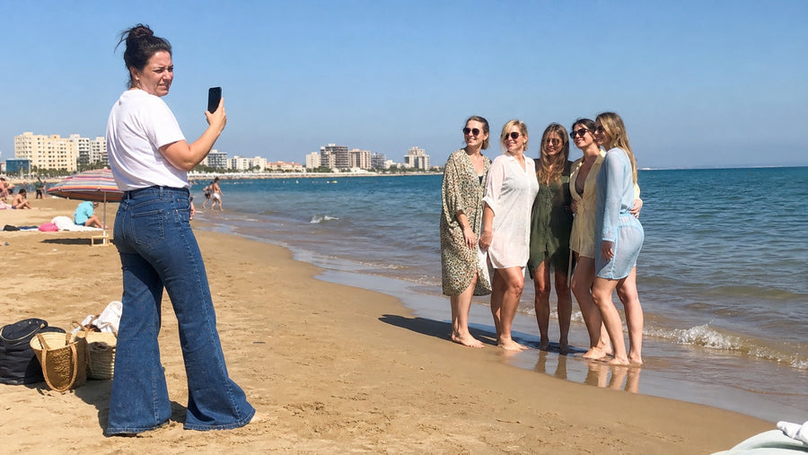 Woman in jeans taking a beach photograph of friends in summer clothes