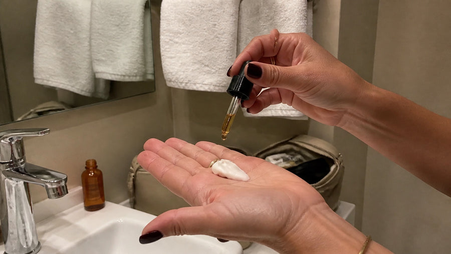 Tanning drops being added to a small amount of moisturiser in a hand